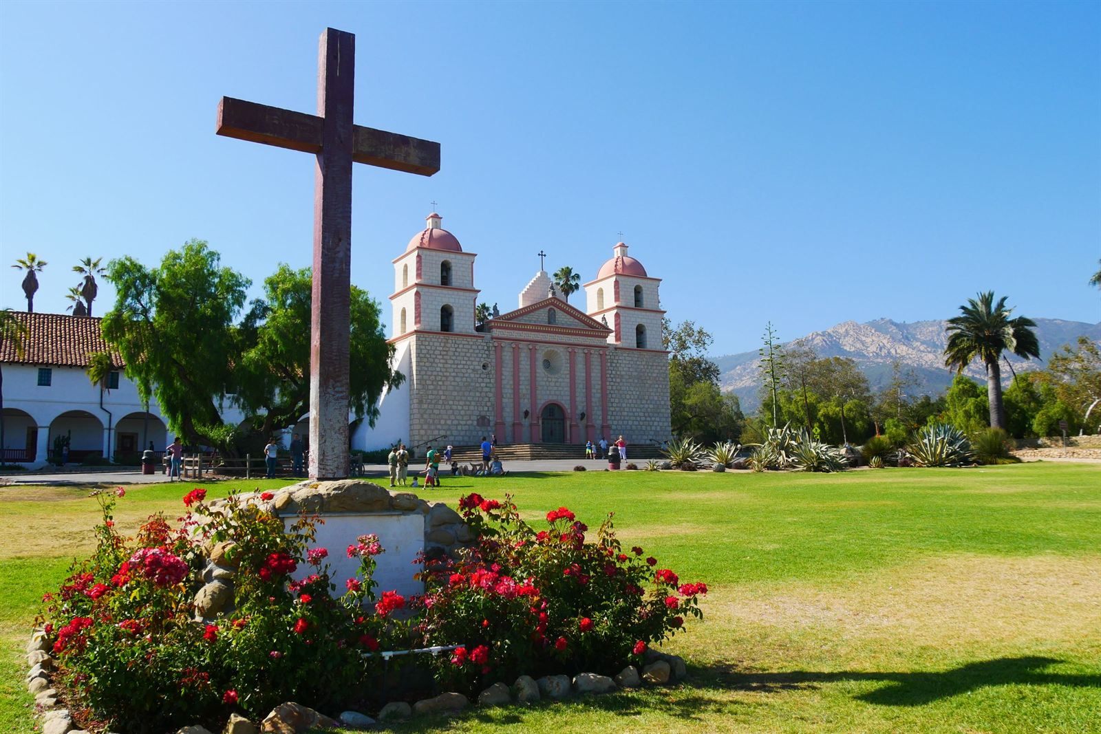 The twin-towered Old Mission Santa Barbara with a wooden cross and red roses, a stop on a Southern California road trip